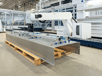 Industrial robotic arm handling a large metal panel in a fabrication facility